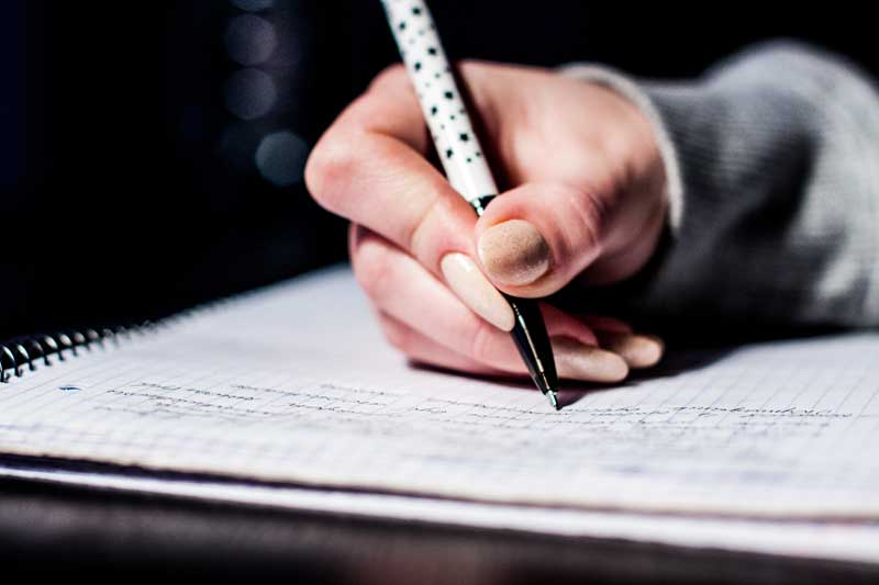 Photo of woman taking notes in a journal.